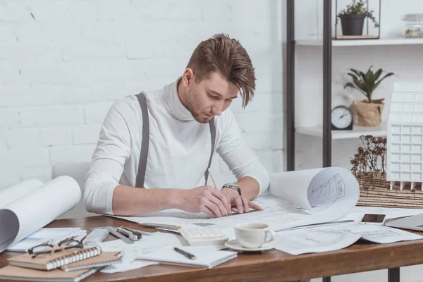 Porträt eines konzentrierten Architekten, der am Arbeitsplatz im Büro an Skizzen arbeitet — Stockfoto