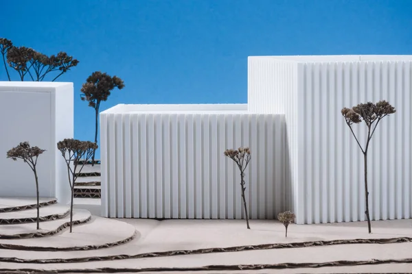 Vue rapprochée du modèle de bâtiment blanc avec des arbres miniatures sur fond bleu — Photo de stock