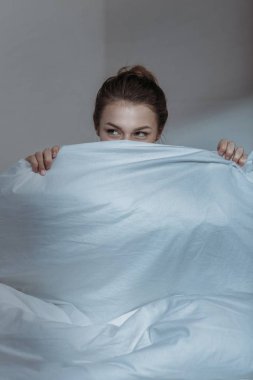 woman covering face with bedcover clipart