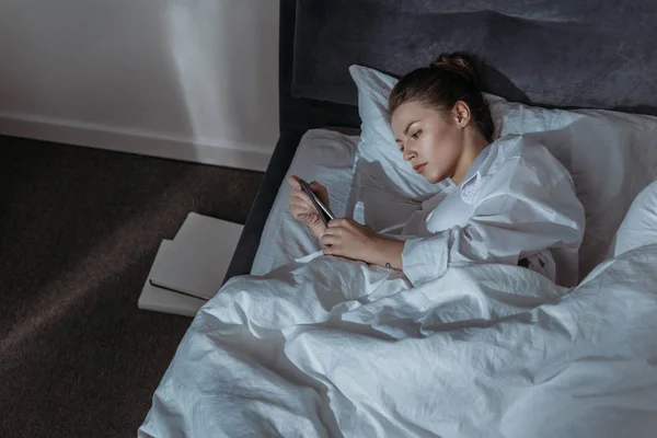 Kvinna som använder telefon i sängen — Stockfoto