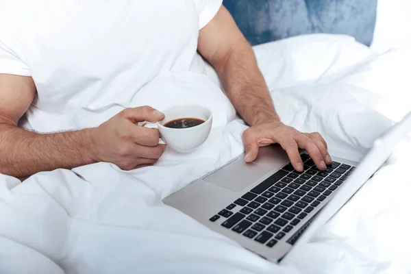 Homem trabalhando no laptop na cama — Fotografia de Stock