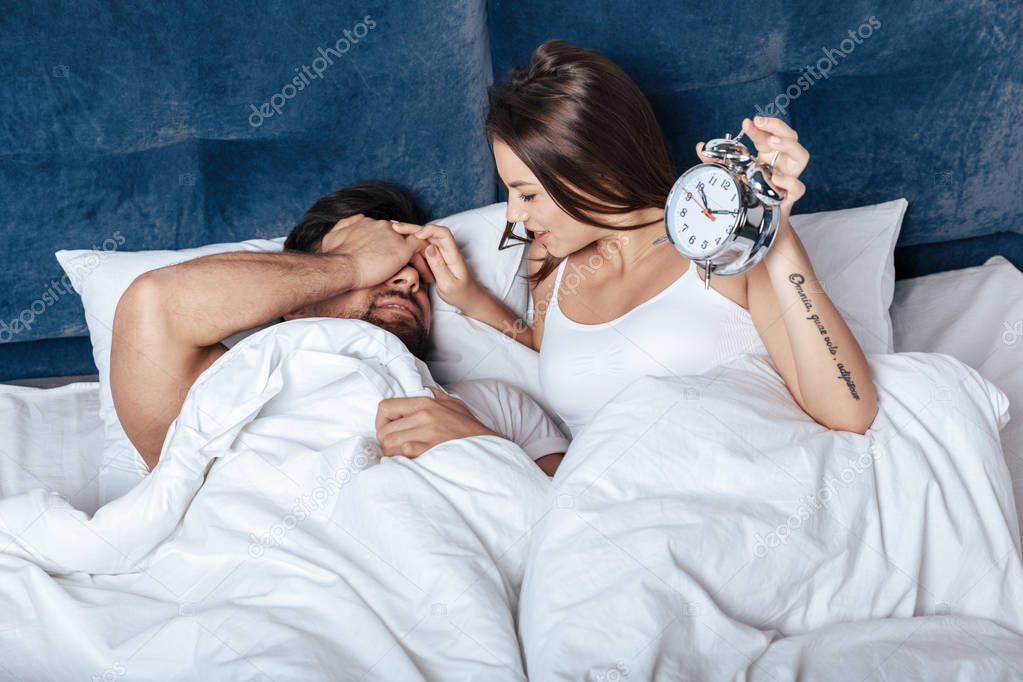 couple waking up with alarm clock