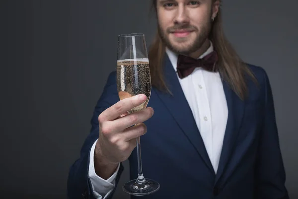 Человек в смокинге держит бокал с шампанским — стоковое фото
