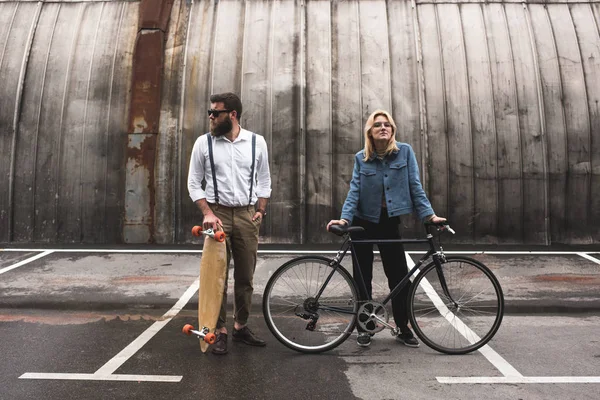 Stylish couple with bicycle and longboard — Stock Photo, Image