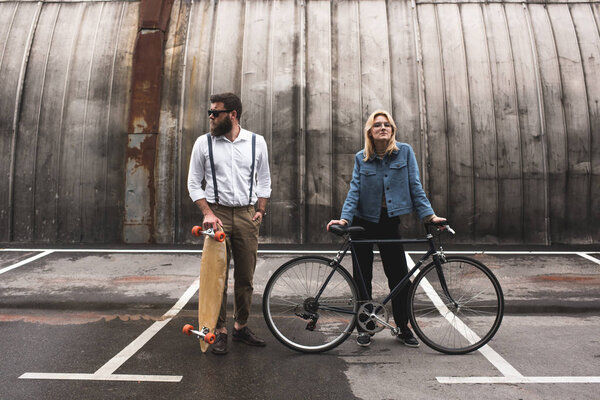 stylish couple with bicycle and longboard