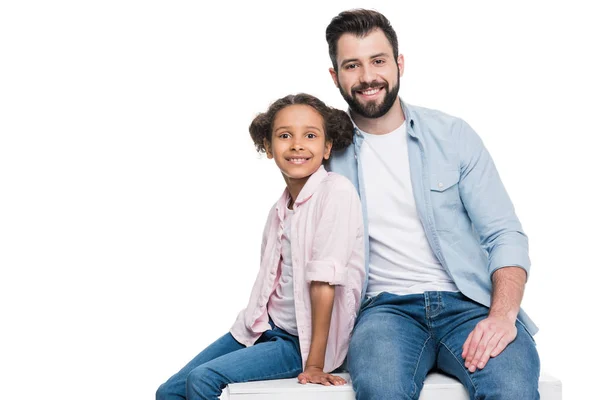 Father and daughter sitting on cube — Stock Photo, Image