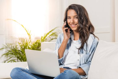 Dizüstü bilgisayar ve akıllı telefon kullanan kadın
