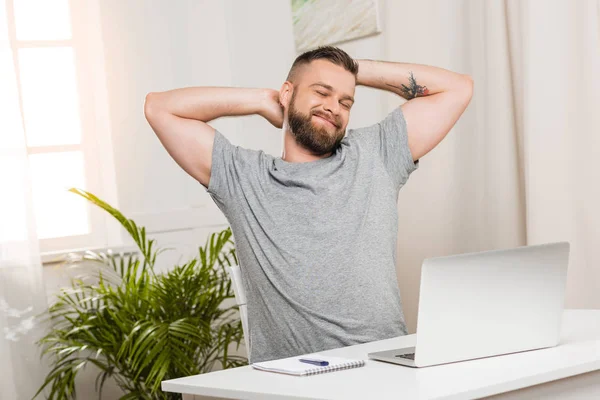 Uomo sorridente seduto sul posto di lavoro — Foto Stock