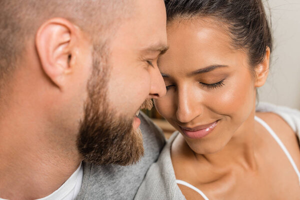 молодые улыбающиеся возлюбленные с закрытыми глазами
