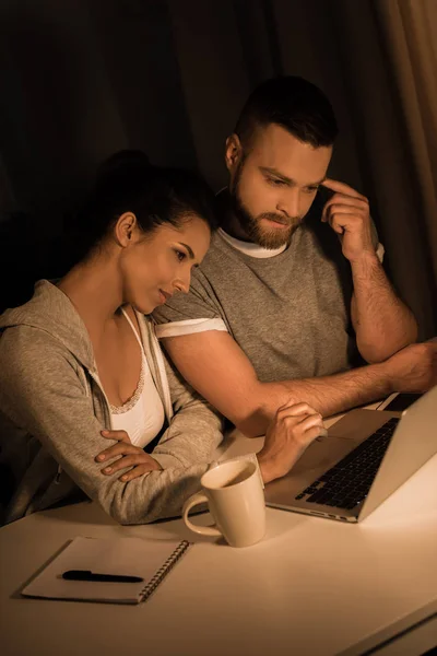 Mietteliäs pari katsomassa kannettavaa tietokonetta kotona — kuvapankkivalokuva