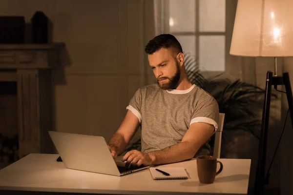 Fundersam man som arbetar på laptop hemma — Stockfoto