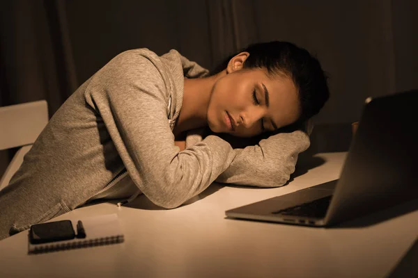 Müde Frau schläft am Tisch neben Laptop — Stockfoto