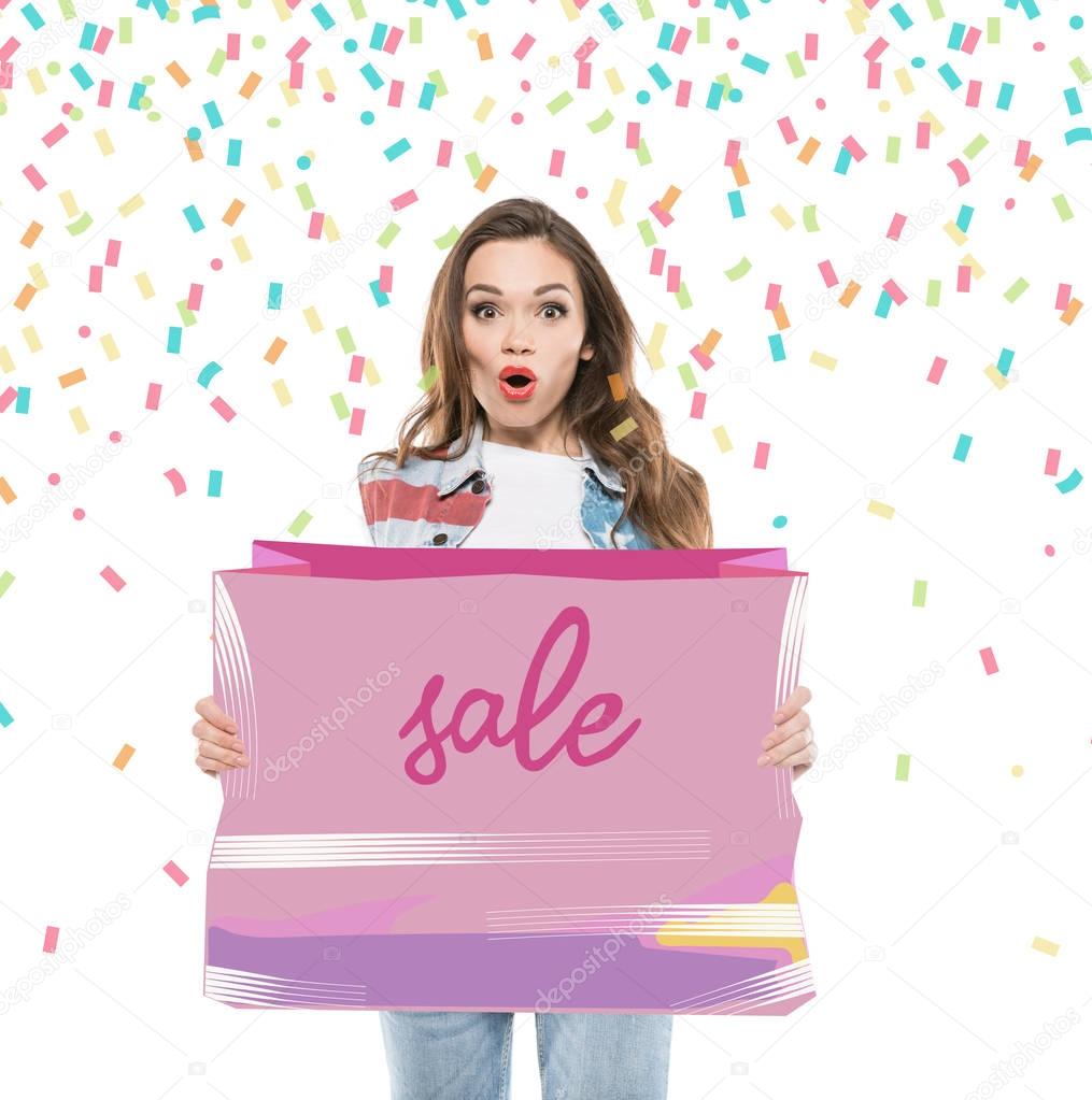 Attractive shocked woman holding pink sale banner with flying confetti