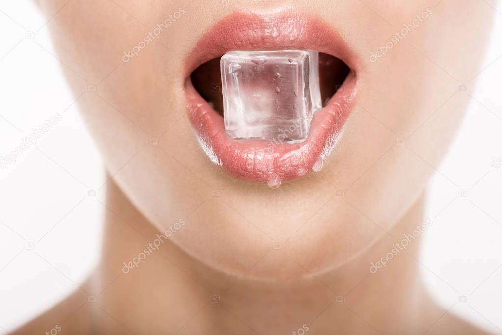 Close up view of seductive woman holding ice cube in mouth, isolated on white