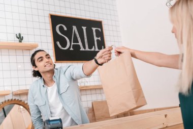 seller giving shopping bag to client clipart