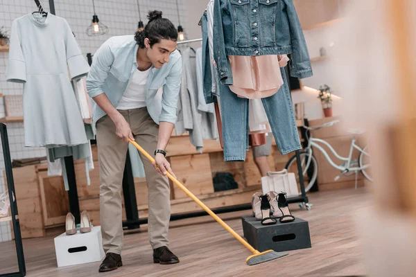 Man sweeping floor in boutique — Stock Photo, Image