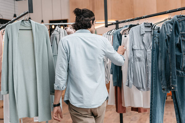 man working with clothes in boutique