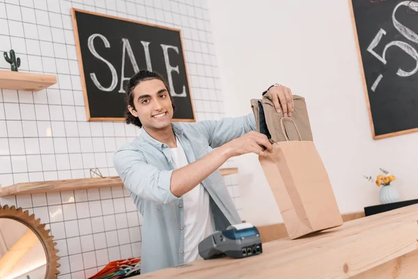 Seller packing clothes in bag — Stock Photo, Image