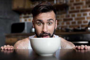 bearded young man looking at breakfast clipart