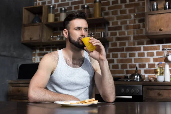 Brodaty młody człowiek pije sok — Zdjęcie stockowe