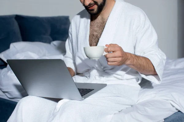 Homem barbudo usando laptop na cama — Fotografia de Stock