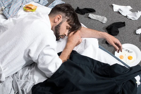 Уставший молодой человек в халате спит — стоковое фото