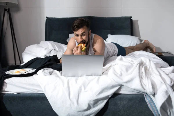 Joven usando el ordenador portátil en la cama — Foto de Stock