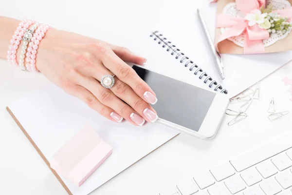 Weibliche Hand mit Smartphone am Arbeitsplatz — Stockfoto