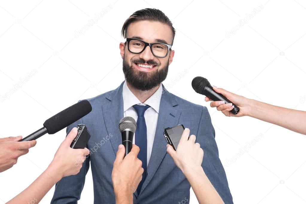 journalists with microphones interviewing businessman