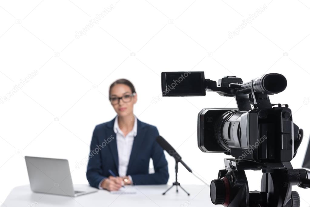 newscaster with laptop looking at camera