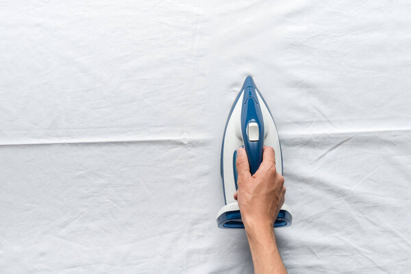 man ironing bed sheets