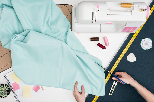 tailor cutting textile with scissors