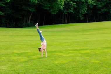 girl performing handstand in park clipart