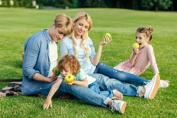 Família comer maçãs no parque — Fotografia de Stock