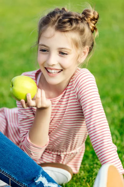 Девушка ест яблоко в парке — стоковое фото