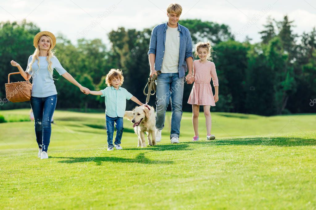 family with dog walking in park