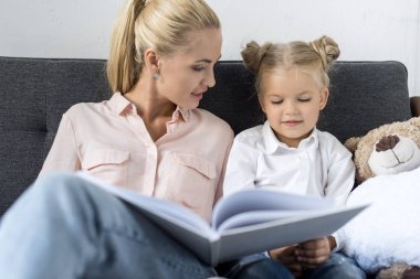 Anne ve kızı kitap okuyor.