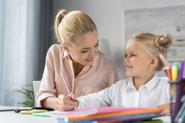Anne ve kızı birlikte çiziyorlar.