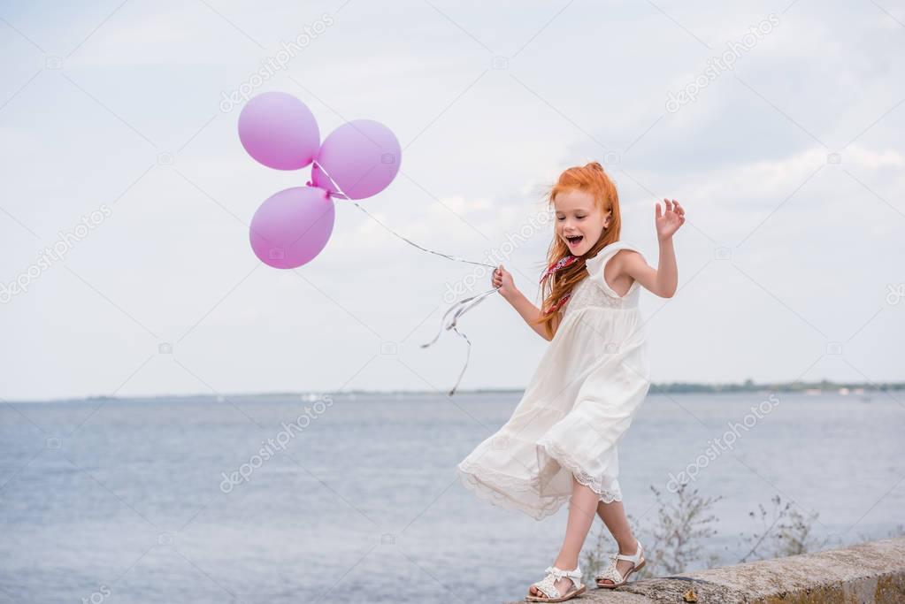 child with balloons on quay 