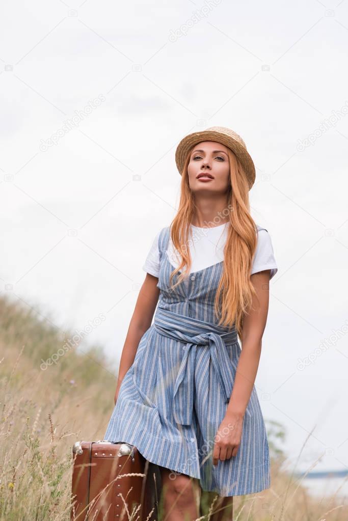 woman with suitcase on grassland