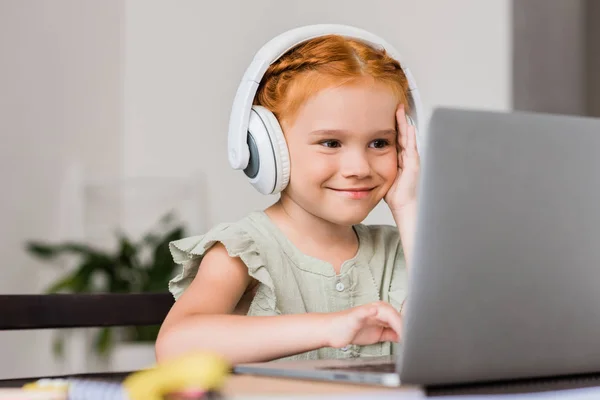 Liten flicka med hörlurar och laptop — Stockfoto