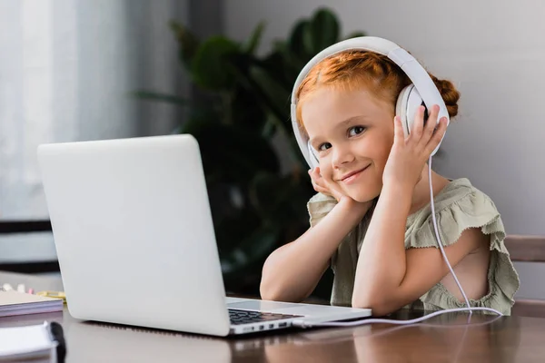 Liten flicka med hörlurar och laptop — Stockfoto