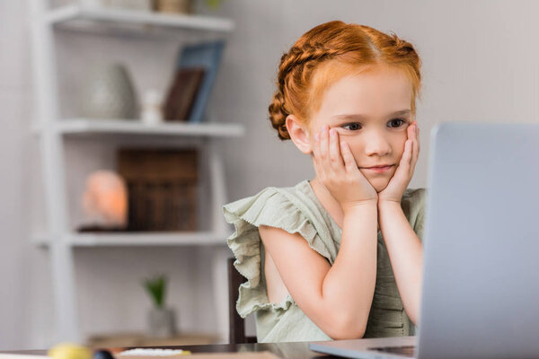 маленькая девочка смотрит на ноутбук
