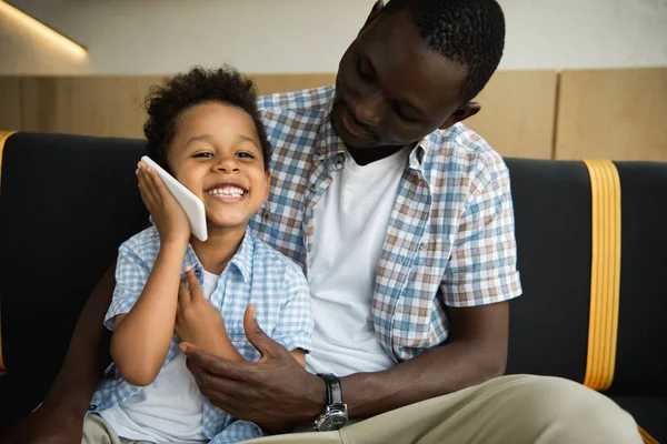 Африканский американский отец и сын со смартфоном — стоковое фото