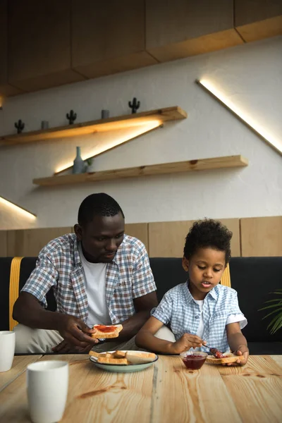 Pai e filho comer torradas — Fotografia de Stock