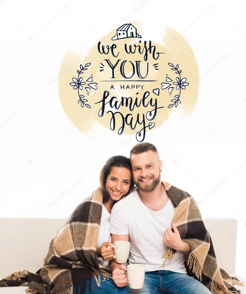 Portrait of young attractive couple having coffee sitting on couch with checkered plaid, isolated on white