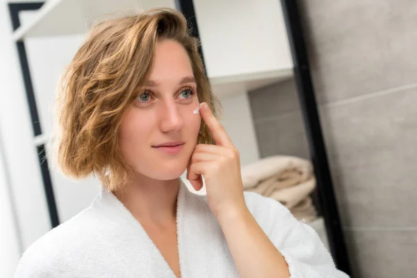 Mujer aplicando crema facial — Foto de Stock