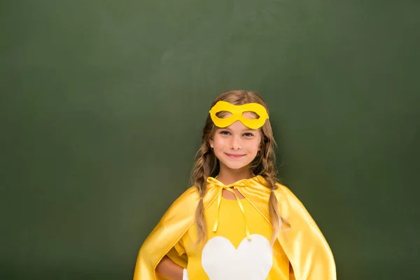 Superhero girl next to green chalkboard — Stock Photo, Image