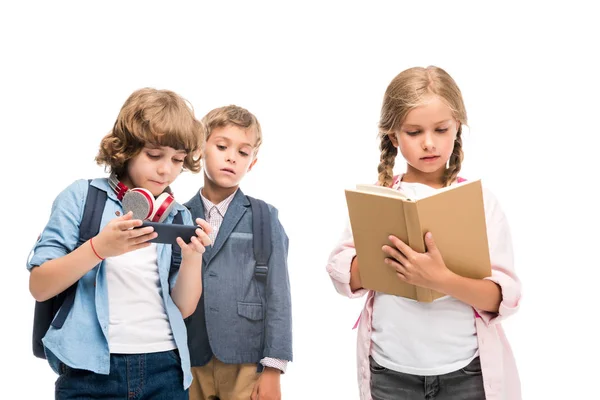 Skolpojkar med smartphone och skolflicka med bok — Stockfoto