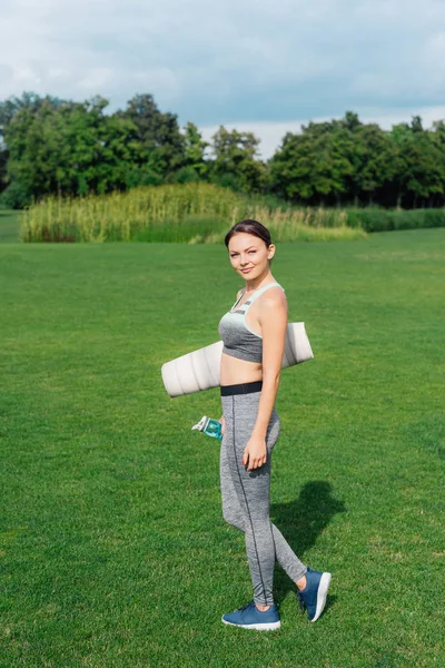 Woman holding water bottle and yoga mat — Stock Photo, Image